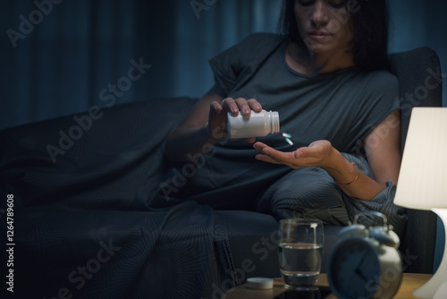Fotografía Young woman taking medications at night