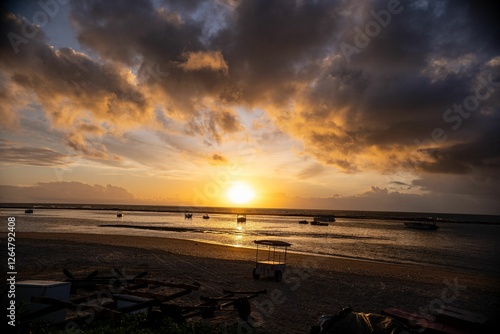 Sunset over a tranquil beach with silhouetted boats.