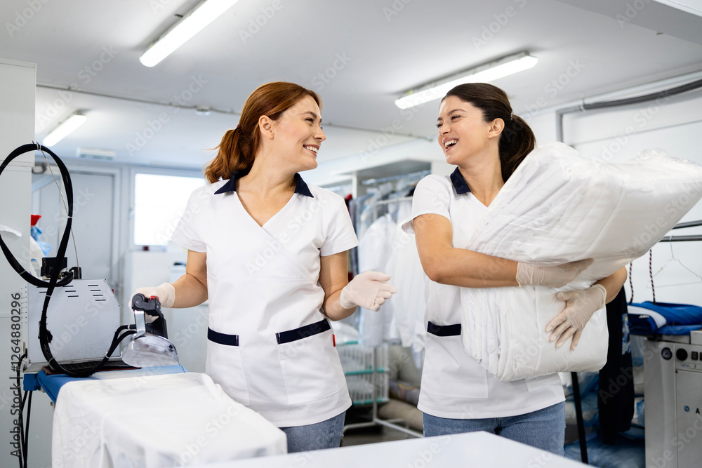 Fototapeta premium Dry cleaner workers ironing and folding clean laundry.