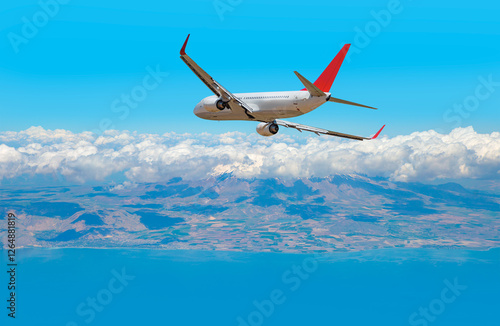 Photography An airplane flying over a taurus mountain range, with snow-capped peaks visible