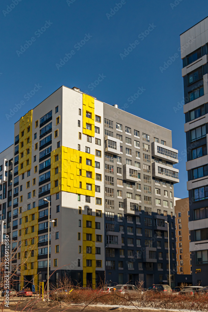 Fototapeta premium Modern apartment buildings with yellow and gray facades against a clear sky