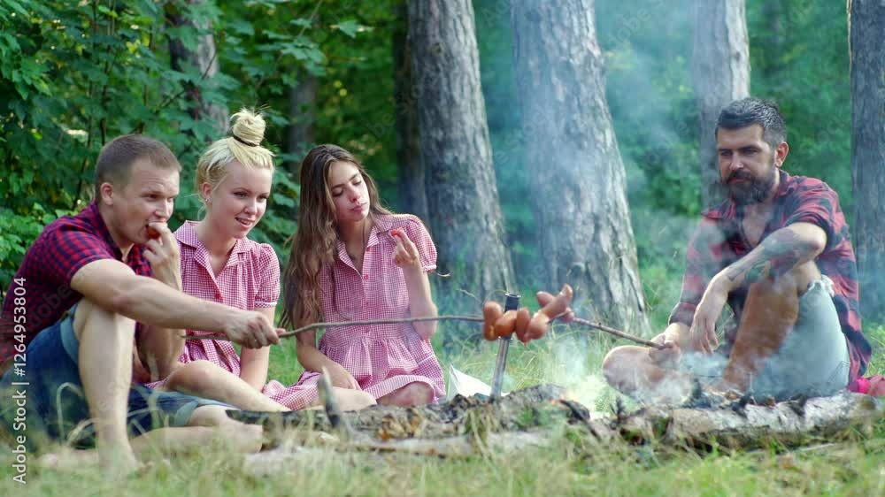 Friends telling stories around the campfire. Happy campers enjoying camp nature together. Summer camping trip with best friends. Tourists eating near a camp fire. Friends enjoying a summer cam.