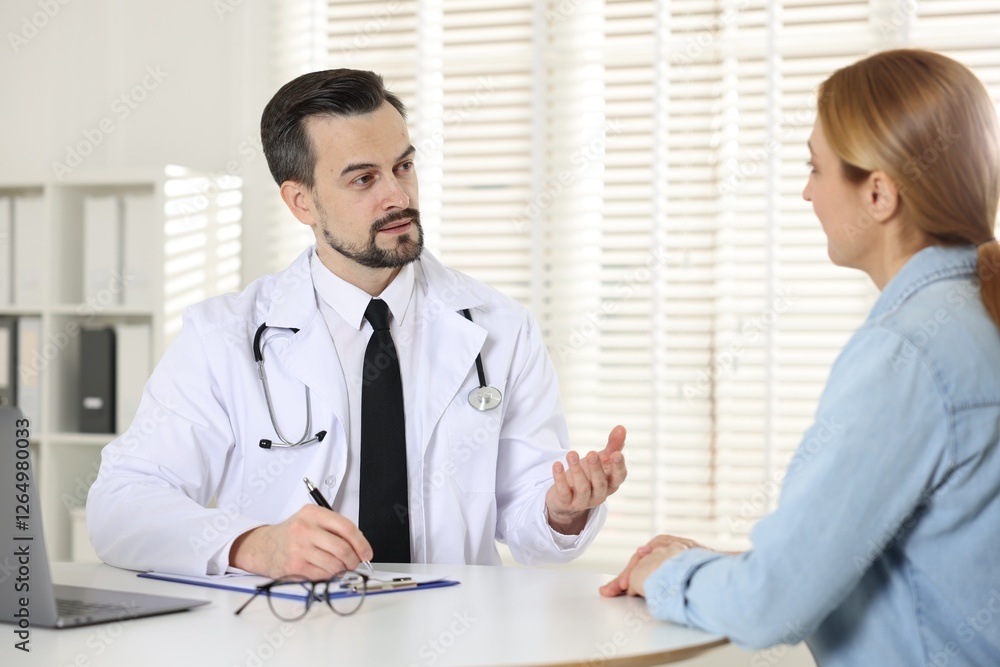 Cardiologist consulting patient at table in clinic Cardiologist consulting patient at table in clinic