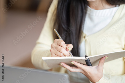 Freelance businesswoman taking notes while brainstorming ideas in her home office, illustrating creativity and planning. photo