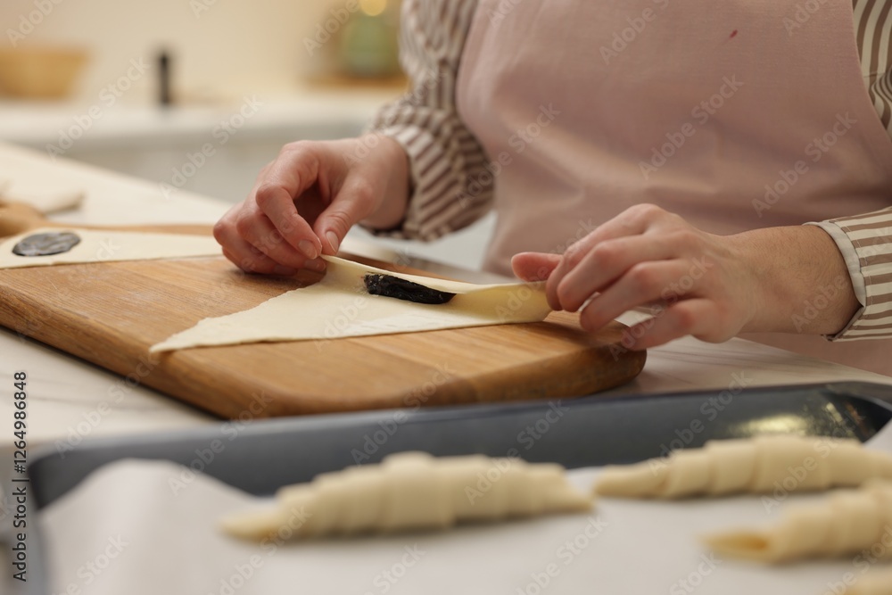 Woman rolling croissant with jam from fresh dough at table, closeup Woman rolling croissant with jam from fresh dough at table, closeup