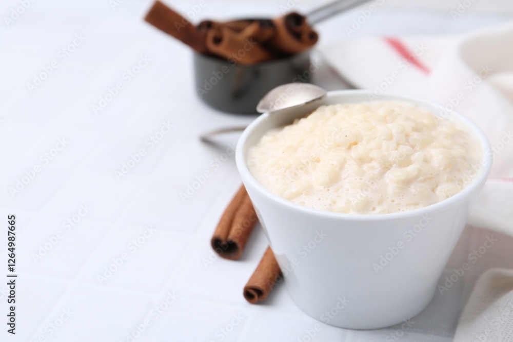Tasty rice pudding with cinnamon served on white tiled table, closeup. Space for text Tasty rice pudding with cinnamon served on white tiled table, closeup. Space for text