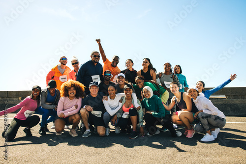 Fotografie Cheerful running club group photo under the bright blue sky
