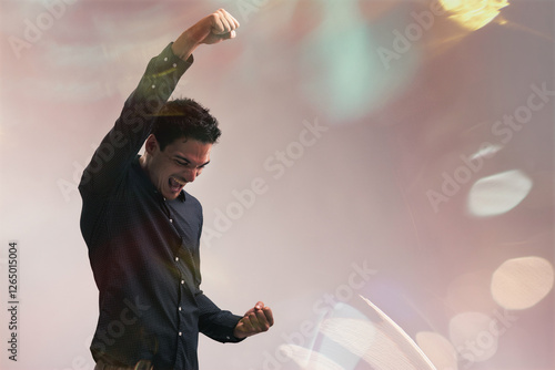 Фотография Young businessman celebrating success with raised arms and clenc