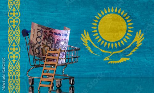 A 10,000 Kazakh tenge banknote in a miniature shopping cart in a photo of the Republic of Kazakhstan flag photo