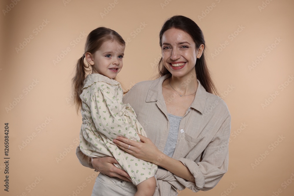 Portrait of happy mother with her cute little daughter on beige background Portrait of happy mother with her cute little daughter on beige background