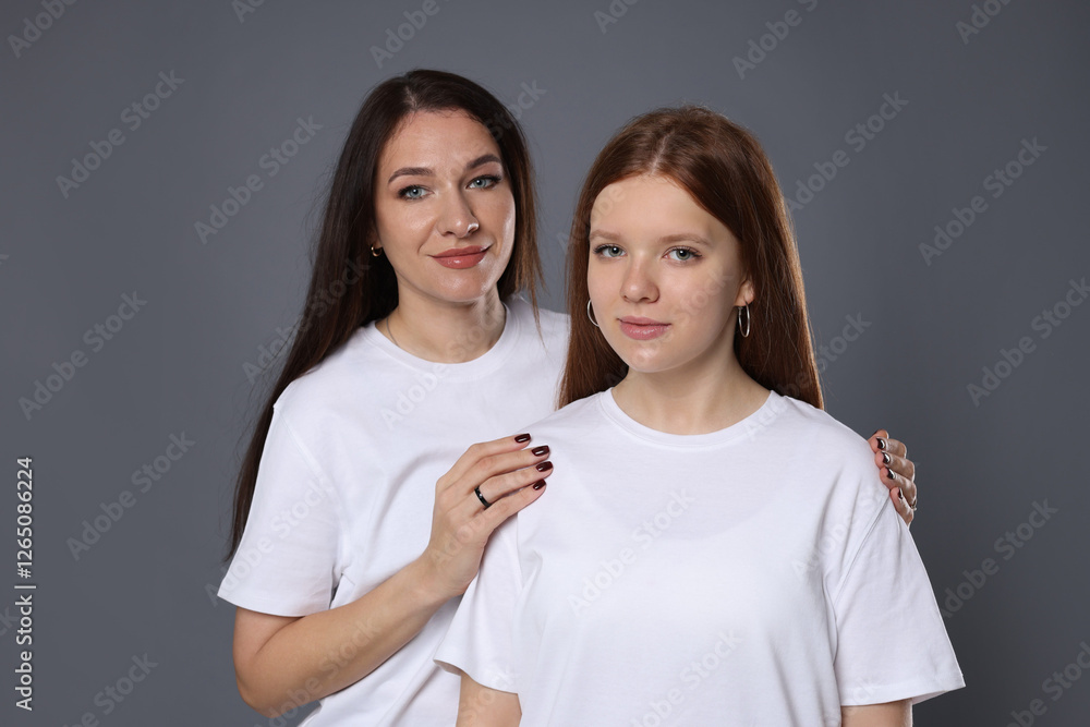 Portrait of beautiful mother with teenage daughter on grey background Portrait of beautiful mother with teenage daughter on grey background
