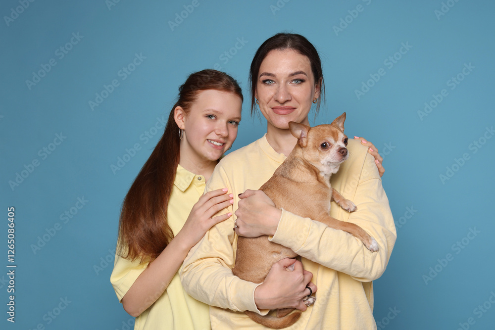 Obraz premium Portrait of beautiful mother with teenage daughter and cute Chihuahua dog on light blue background