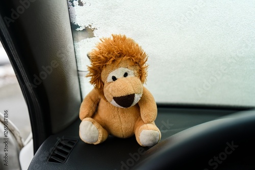 Stuffed Lion Toy Sitting on Car Dashboard Near Frosted Window