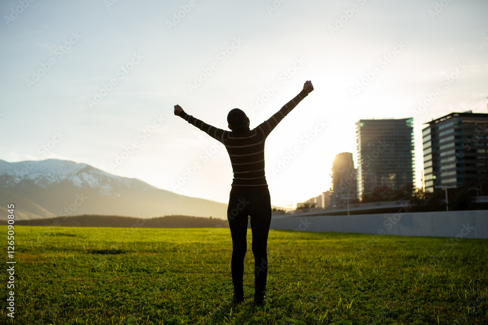 Silhouette of a woman celebrating outdoors with arms raised at sunset Silhouette of a woman celebrating outdoors with arms raised at sunset