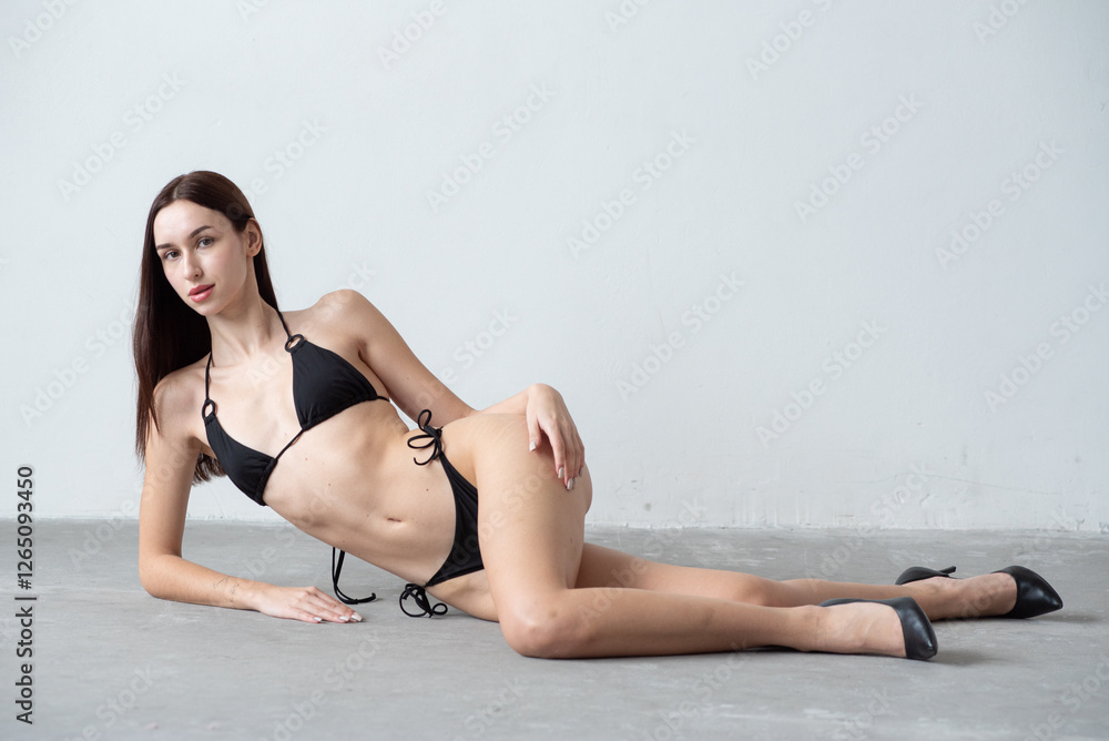 Obraz premium Professional test shoot featuring a model in a black bikini against a neutral background. Fresh-faced, natural beauty, and clean aesthetic—ideal for casting agencies, portfolios, and fashion industry