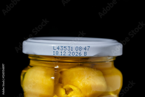 Foto Glass jar of pickled champignon mushrooms with white lid with expiration date, c
