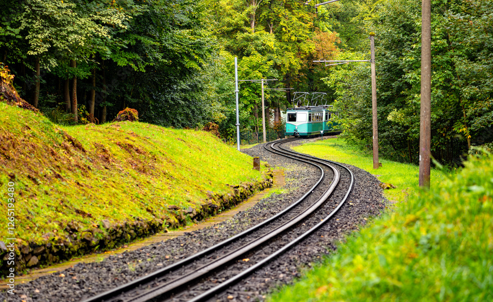 Fototapeta premium The historic cog railroad that transports tourists up the Drachenfels near Bonn is the oldest in Germany. Panorama with electric railcar traveling along the winding route to the mountain station. 