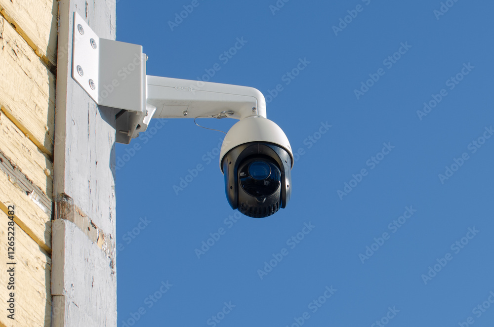 A modern security camera with a blue sky in the background. A modern security camera with a blue sky in the background.