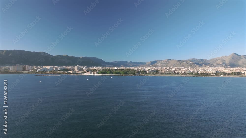 A cruise ship approaches Palermo, offering a stunning view of the city skyline, coastline, and surrounding mountains. The calm blue sea and scattered boats complete the scenic arrival. A cruise ship approaches Palermo, offering a stunning view of the city skyline, coastline, and surrounding mountains. The calm blue sea and scattered boats complete the scenic arrival.