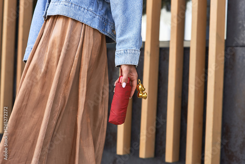 Obraz na płótnie Fashionable person holding red umbrella with golden keychain while walking in urban setting, stylish accessory concept w salonie
