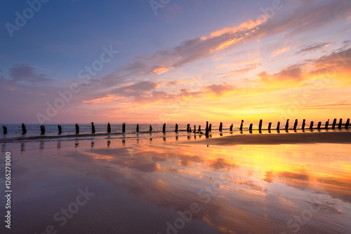 Old sea defence groynes used to protect coastlines from erosion at sunset. Walney, Lake District, UK. photo