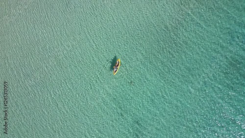 Woman and dog drone aerial top view with life jackets on a yellow kayak on a Diaporos greek island with turquoise water