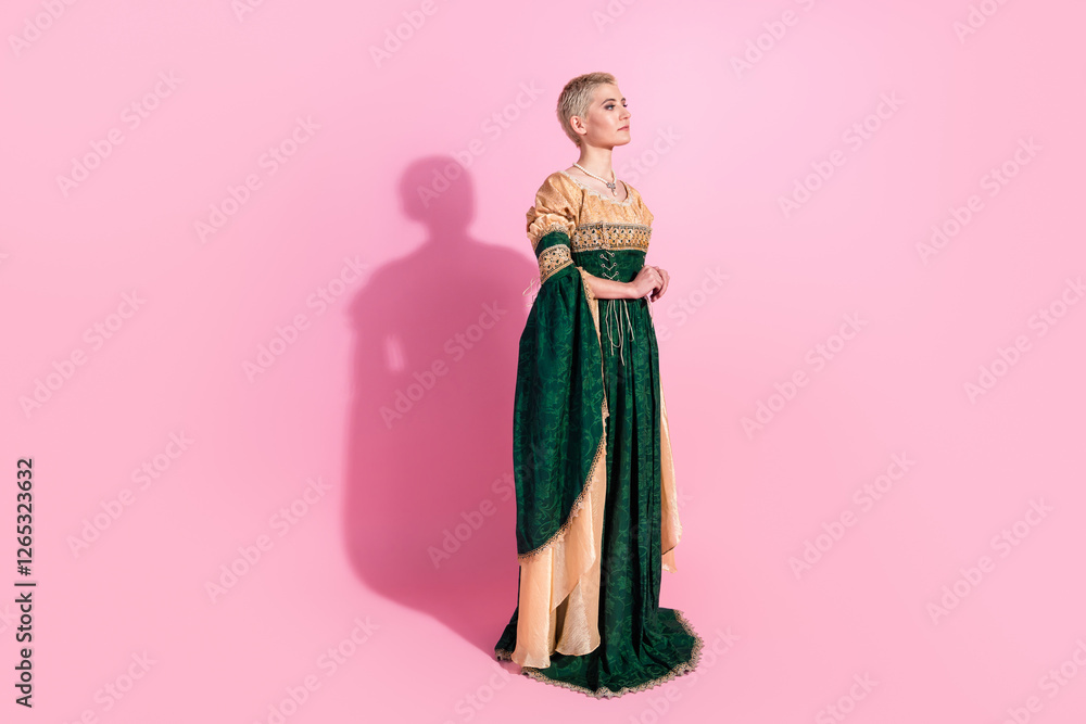 Fototapeta premium Young woman in medieval attire against a pink background showcasing elegance