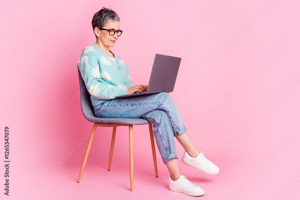 Elderly Woman Using a Laptop on a Colorful Pink Background, Radiating Casual Style and Elegance Elderly Woman Using a Laptop on a Colorful Pink Background, Radiating Casual Style and Elegance