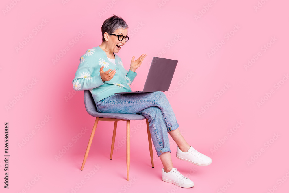 Charming mature woman using a laptop in a colorful setting with a cheerful expression Charming mature woman using a laptop in a colorful setting with a cheerful expression