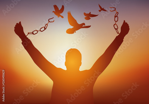 Concept de la liberté, avec un homme qui brise ses chaînes et qui voit s’envoler des colombes de la paix devant un coucher du soleil.