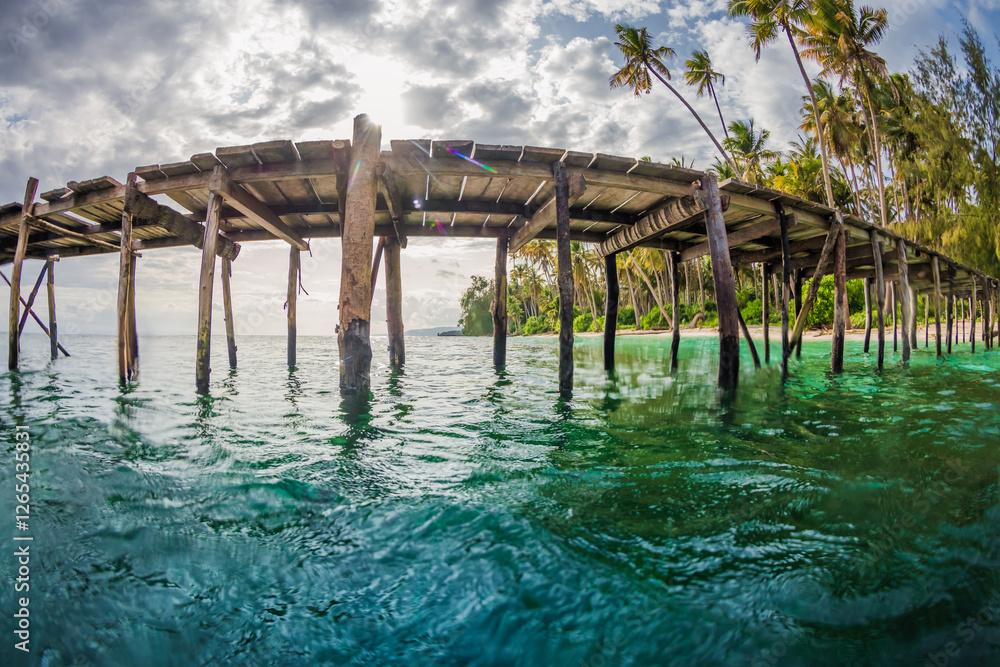 Fototapeta premium Tropical coast line with wooden pier in quiet sea in Indonesia. Fisheye shot