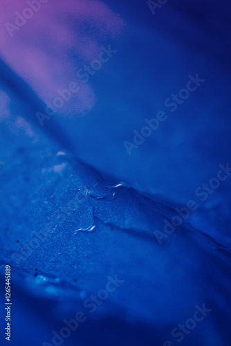 Extreme close up of blue empty plastic bag background. The plastic surface is wrinkly and tattered making abstract pattern. Selective focus, shallow depth of field.