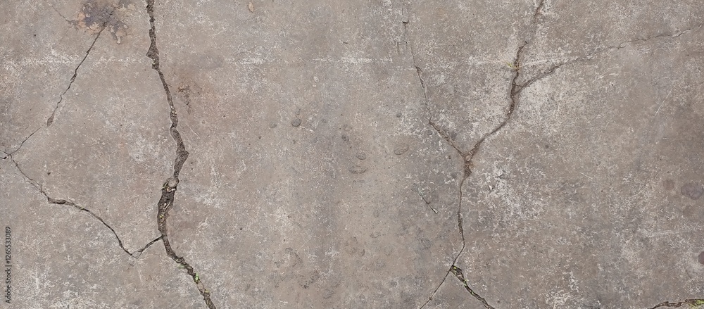 Fototapeta premium Cracked concrete surface with a linear pattern, illuminated by natural light