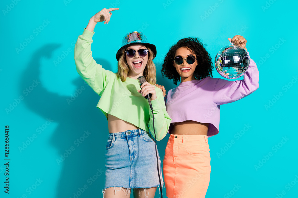 Εκτύπωση καμβά Two fashionable women enjoying fun moments with accessories against a turquoise