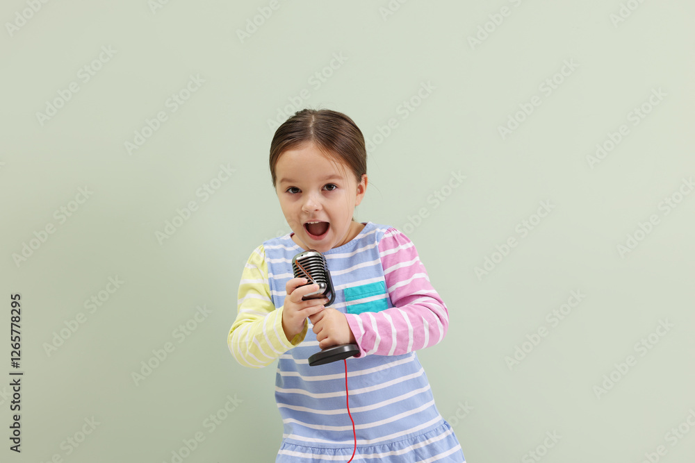 Cute girl with microphone singing near green wall Cute girl with microphone singing near green wall