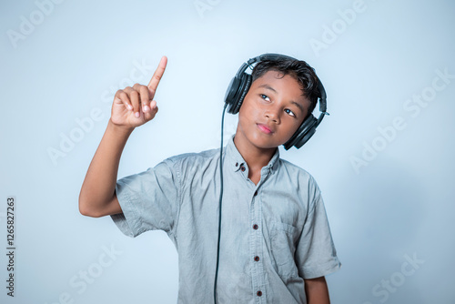 Boy is listening to something through headphones. Indonesian people photo