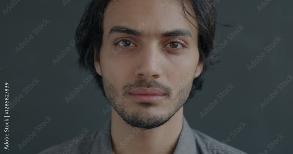 Close-up portrait of confident Middle Eastern man looking at camera with serious face on black background. Individuality and emotion concept. Close-up portrait of confident Middle Eastern man looking at camera with serious face on black background. Individuality and emotion concept.