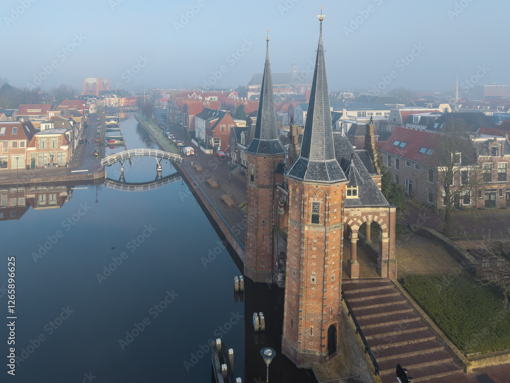 Naklejka premium Drone aerial of historic Sneek Waterpoort, water gate tower and tower in soft warm morning light