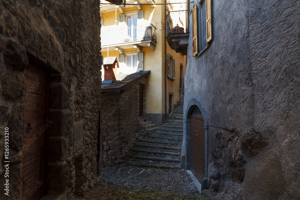 Street view of historical village Gromo, Bergamo, Lombardy, Italy. Narrow cobbled streets. Sun lights and shadows.