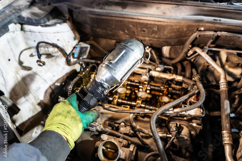 A mechanic's hand holding a work light over a disassembled engine, showing camshafts and internal components engine. photo