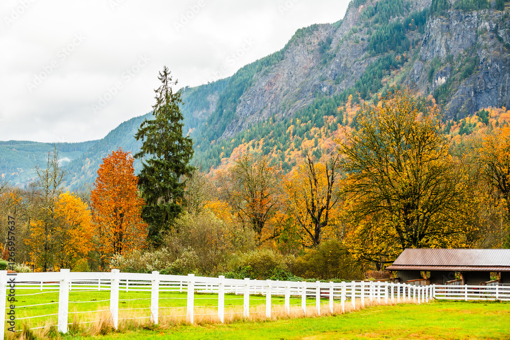 Idyllic farm with fall colors and a white fence against hillside. Idyllic farm with fall colors and a white fence against hillside.