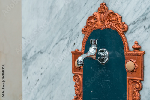 Obraz na płótnie Side view of a vintage ornamental water basin and faucet mounted on a marble wall. Golden ornaments at side. w salonie