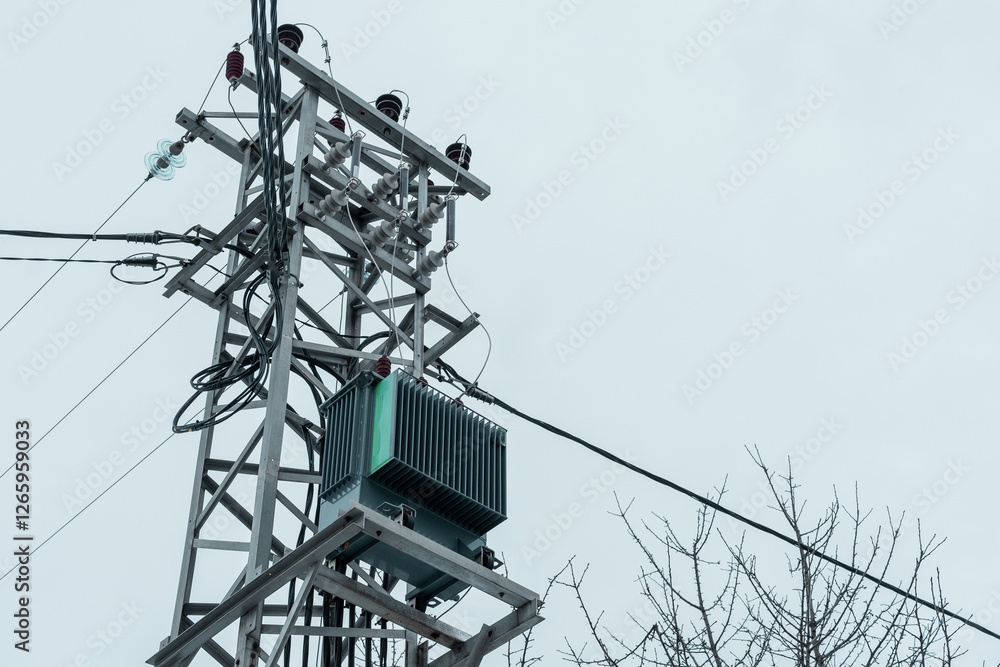 Smal transformer station on the top of power line pole. Frog view of a voltage transformer in a small village