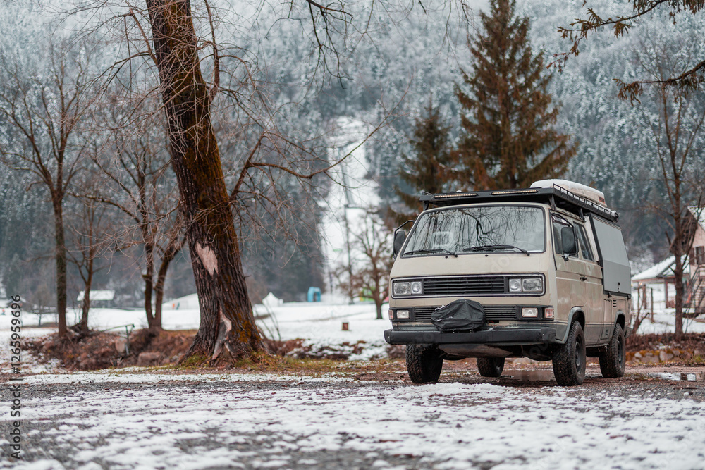 Vintage adventure campervan is parked on the snow capped campsite in Ljubno, Slovenia, on a snowy winter day. Old campervan in action
