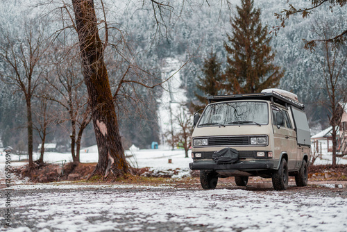 Vintage adventure campervan is parked on the snow capped campsite in Ljubno, Slovenia, on a snowy winter day. Old campervan in action photo