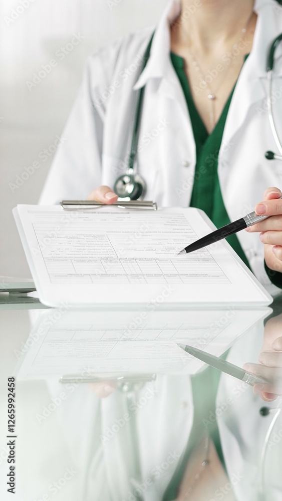 Female doctor in a hospital setting is pointing at medical chart, showcasing expertise in a close up shot. Medicine