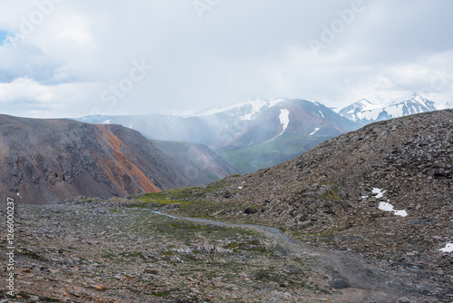 Atmospheric misty alpine landscape with mountain stream in stony hanging vall...