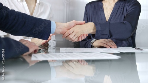 Photos Unrecognizable business partners shaking hands after signing contract at glass t