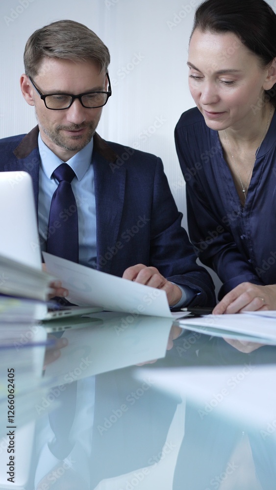 Colleagues in a modern office environment collaborating on a project, analyzing documents, and utilizing a laptop. Business people concept Colleagues in a modern office environment collaborating on a project, analyzing documents, and utilizing a laptop. Business people concept