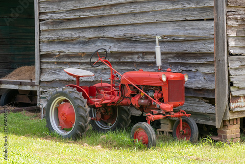 Fotografija old red tractor parked by barn